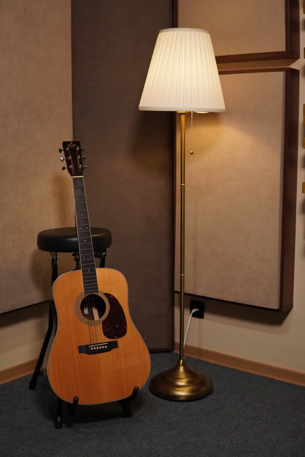 Akustična gitara na zidu pored lampe u sobi za snimanje Oktava